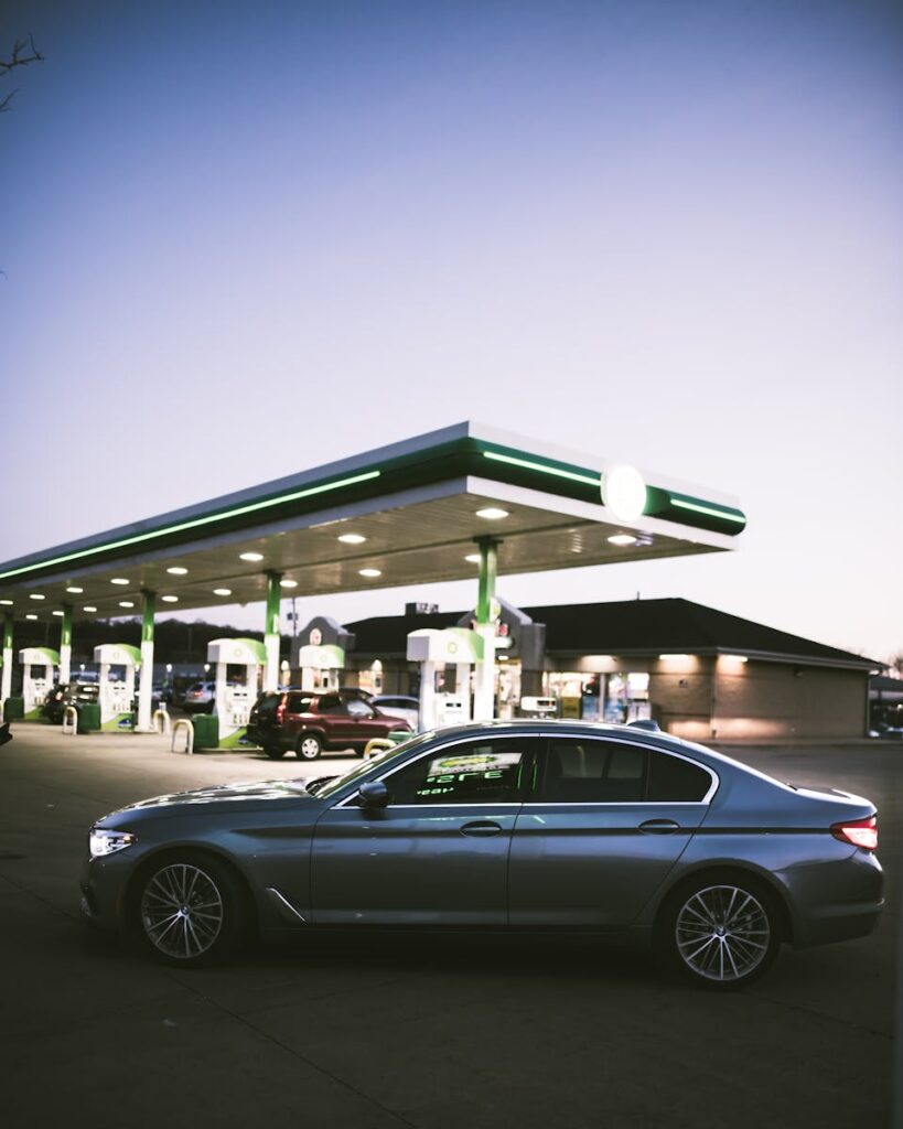 A sleek luxury sedan parked at a gas station during twilight in Des Moines, Iowa.