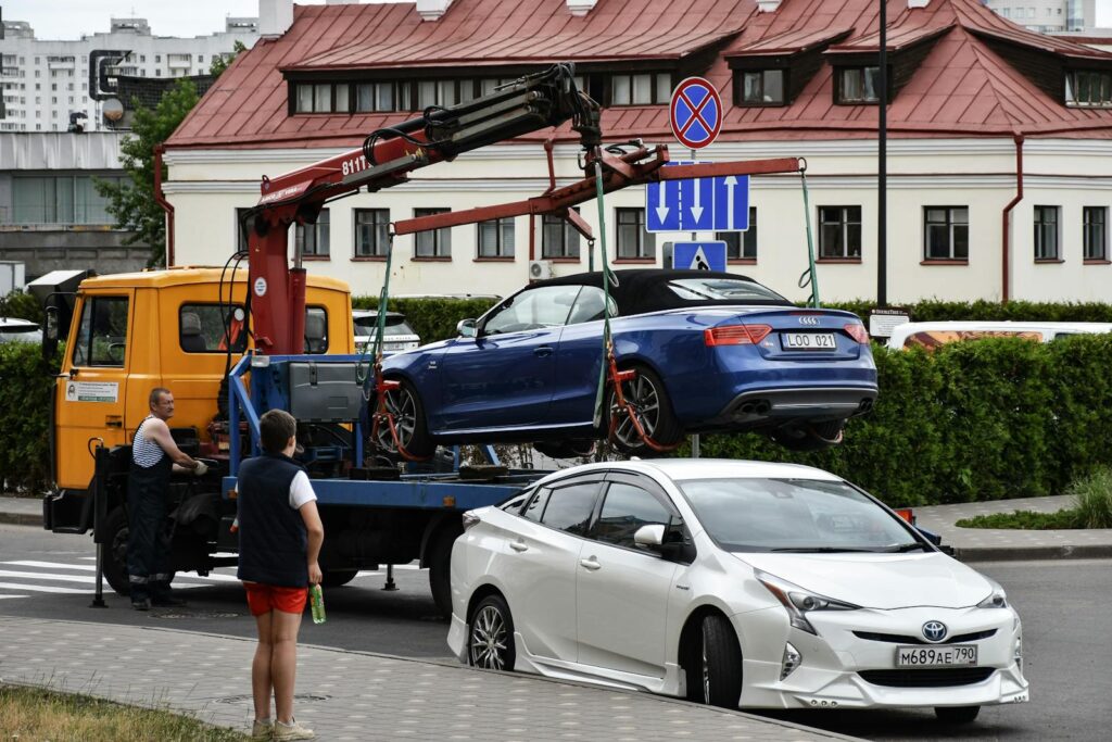 Towing a blue Audi convertible in a bustling city street.