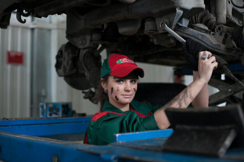 Female mechanic maintaining a car in an auto repair shop, showcasing skill and concentration.