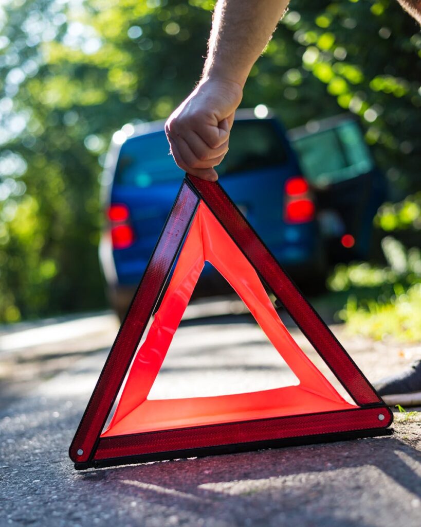 Close-up of a hand placing an emergency warning triangle by a car.