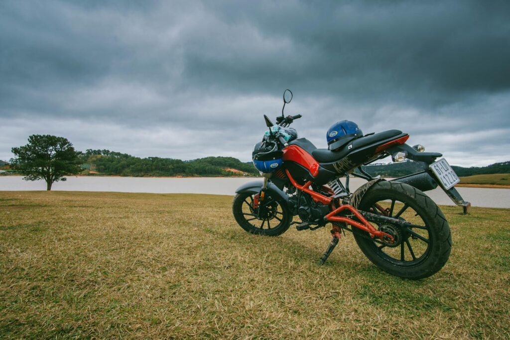 A scenic view of a parked motorcycle near a calm lake under stormy clouds, capturing the essence of adventure and nature.