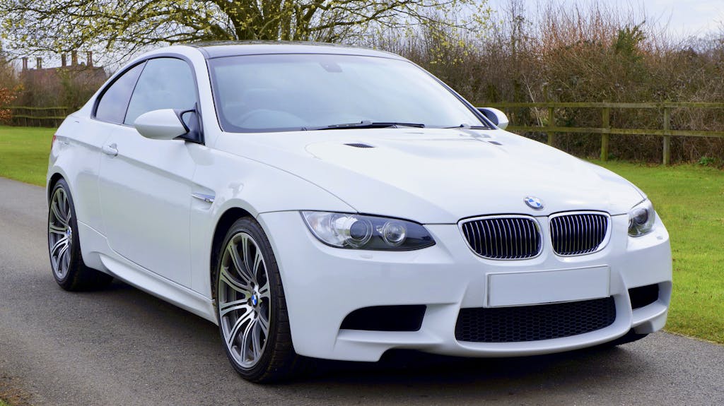 A sleek and stylish white BMW coupe car parked on a paved road, perfect for luxury transportation.