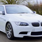 A sleek and stylish white BMW coupe car parked on a paved road, perfect for luxury transportation.