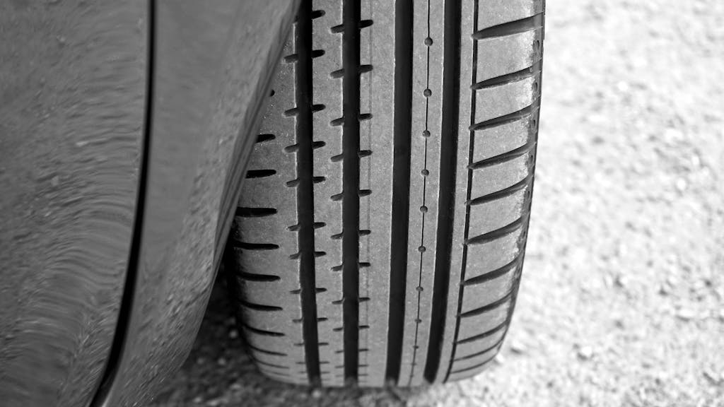 Detailed view of vehicle tire on a gravel surface, showcasing tread pattern.