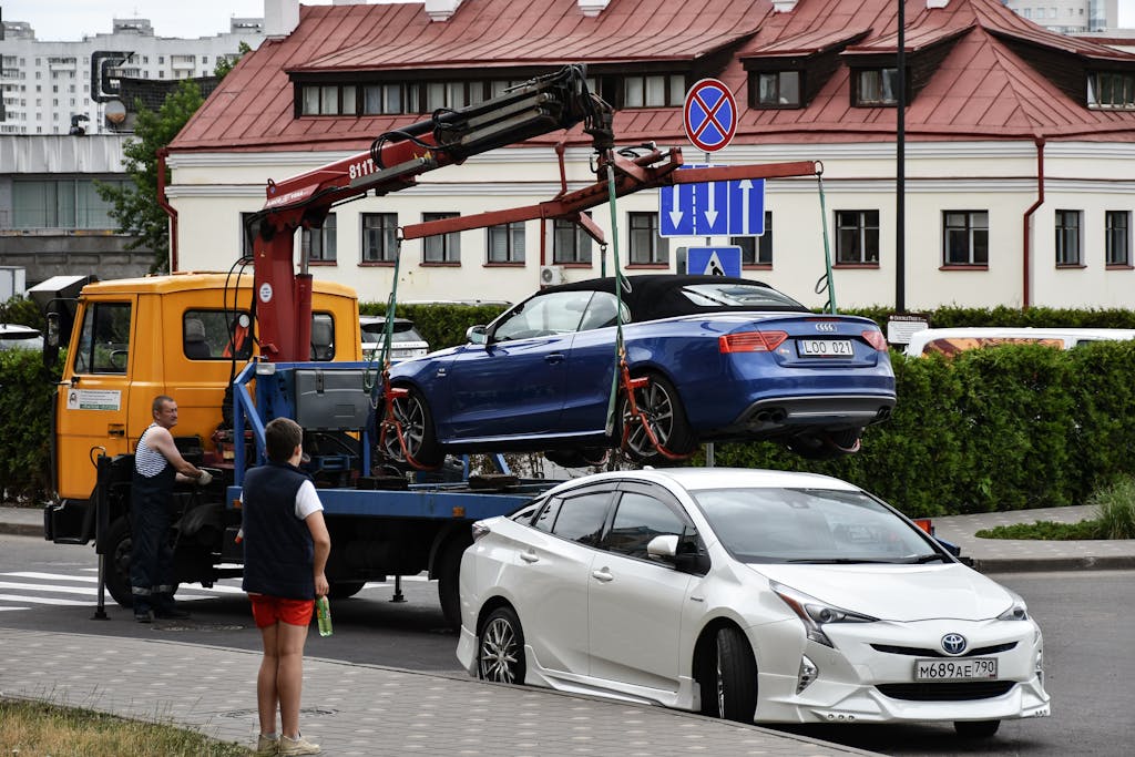 Towing a blue Audi convertible in a bustling city street.